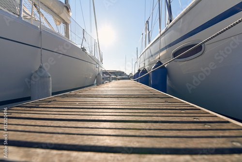 Marina with anchored boats.
Perspective of small floating pier on still water.