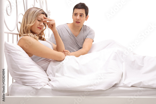 Sad woman lying in bed with a guy comforting her