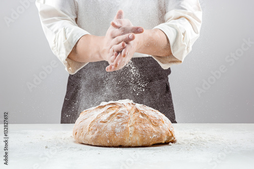 Fényképezés The male hands in flour and rustic organic loaf of bread