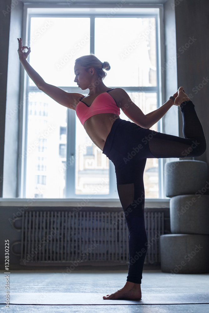 Young woman in yoga class, standing bow pose Young woman in yoga class, standing bow pose