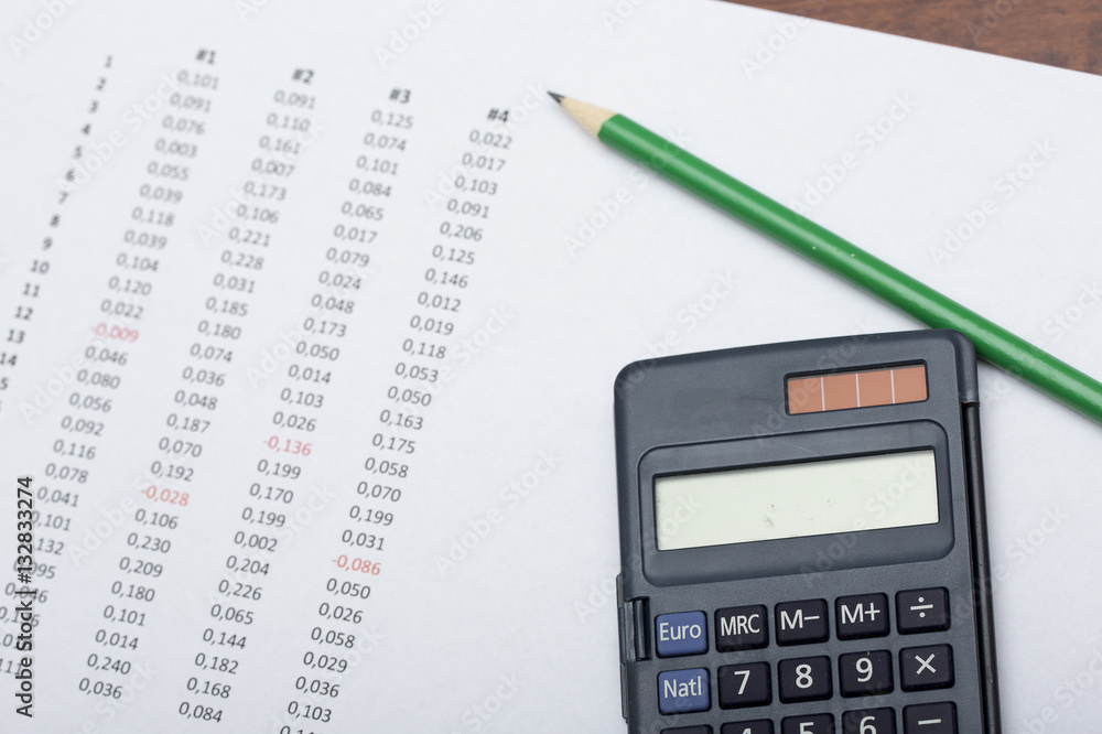 Business concept image. Calculator, pencil, figures on a paper sheet. Some of the numbers are marked red. Business concept image. Calculator, pencil, figures on a paper sheet. Some of the numbers are marked red.