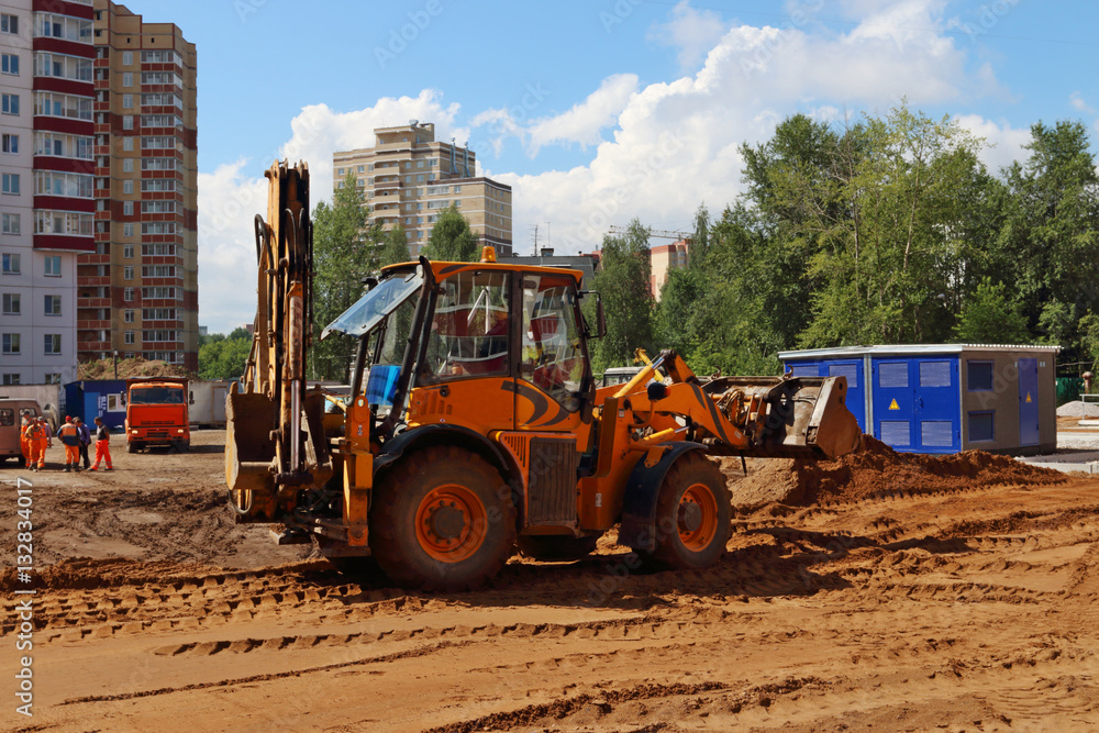 Obraz premium Yellow tractor works on construction site at summer sunny day