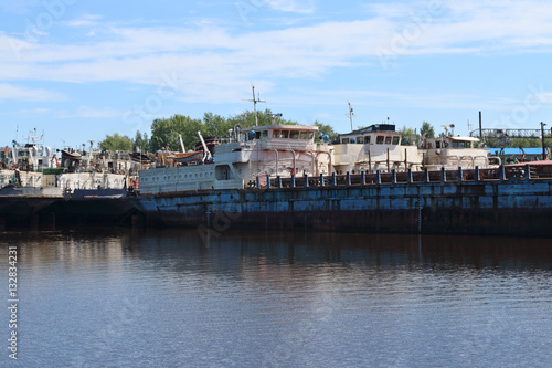 Big rusty cargo ships are in bay on river at summer sunny day