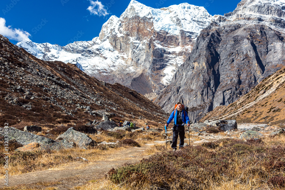 Mountain Hiker walking on Footpath with high Peaks on Background