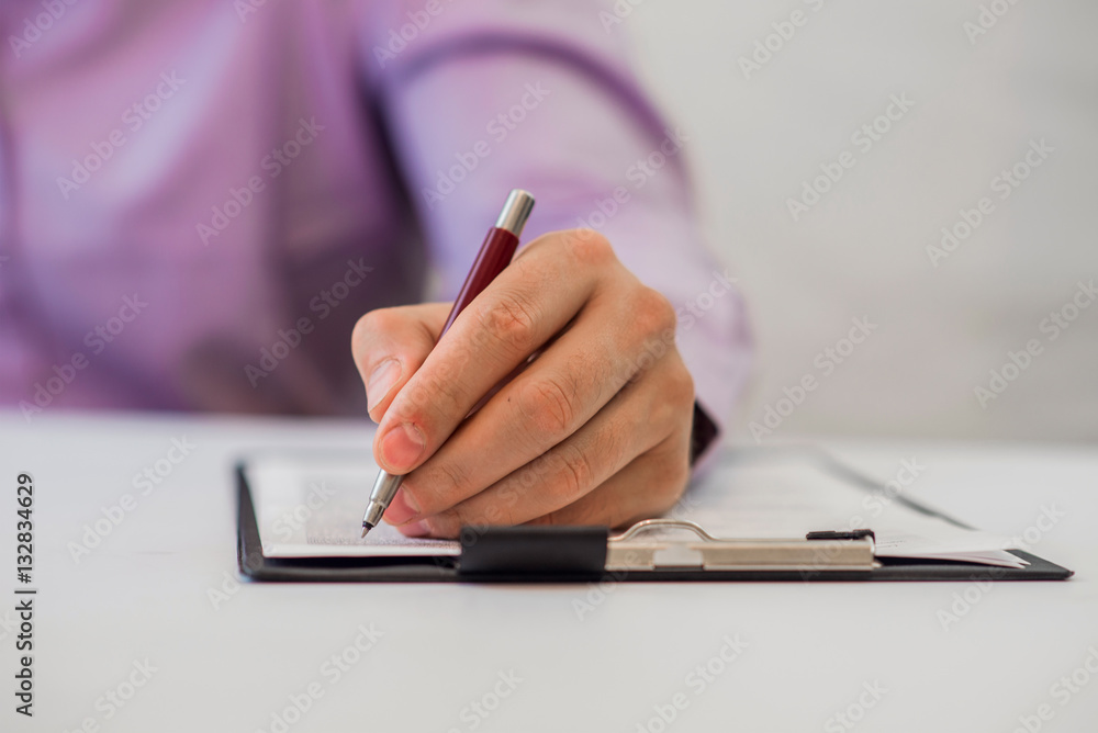 Detail shot of a business man writing on paper using pen Detail shot of a business man writing on paper using pen