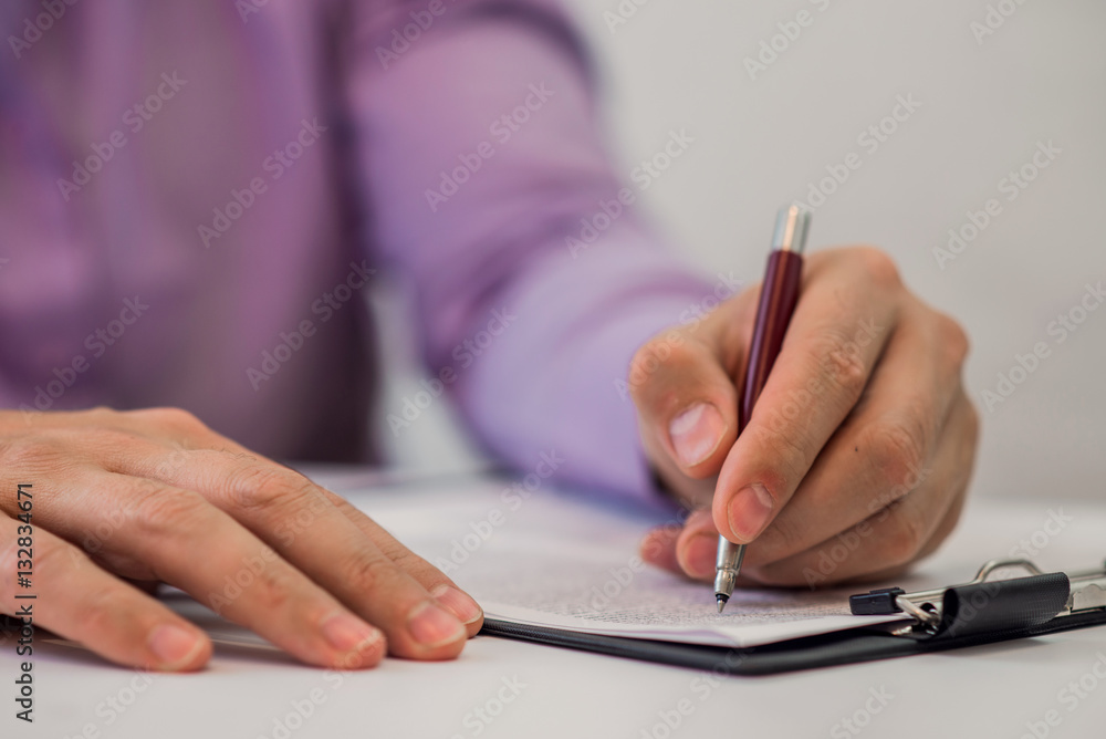 Detail shot of a business man writing on paper using pen Detail shot of a business man writing on paper using pen