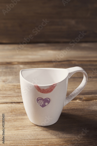 White Cup with painted heart and lipstick  Valentine s day  on the background of old wooden planks