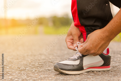 Fototapeta Naklejka Na Ścianę i Meble -   Man tying shoes at roadside.Or sport man tying shoes