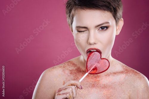 Pleasant young woman licking lollipop