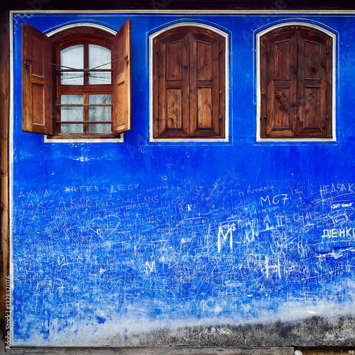 Blue painted facade wall with timber windows and graffity photo