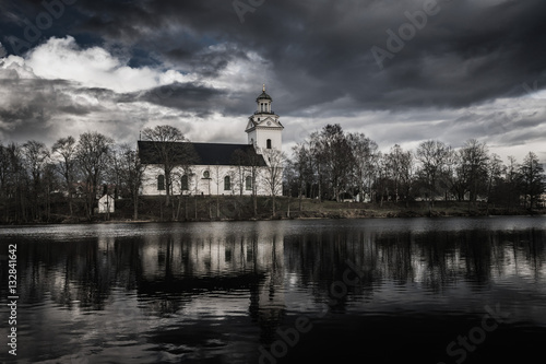 White church in a dark and scary environment with black water and a dramatic cloudy sky