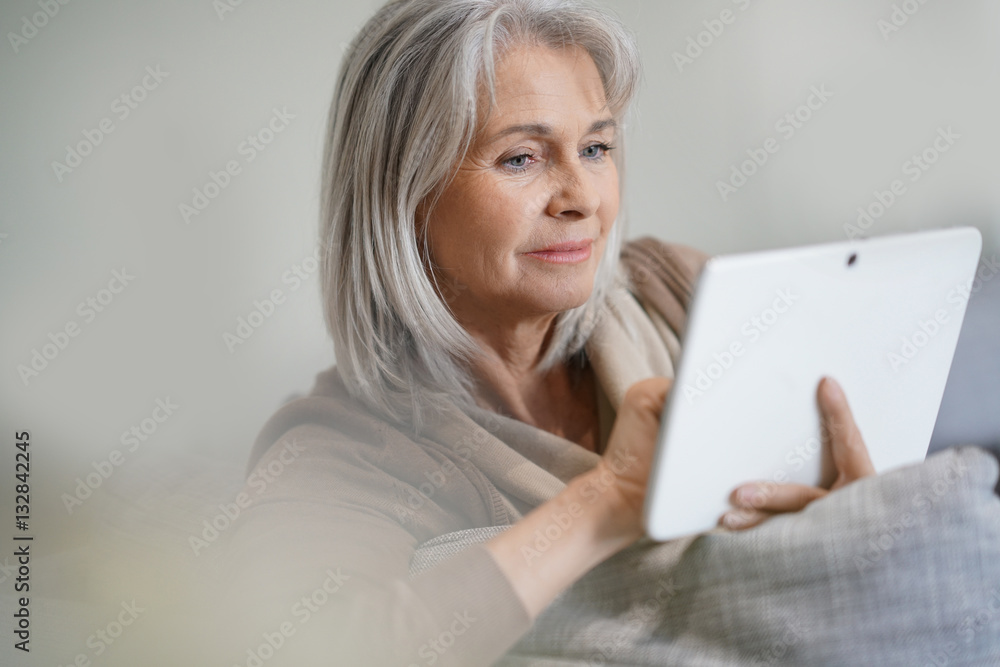 Senior woman at home connected on digital tablet Senior woman at home connected on digital tablet