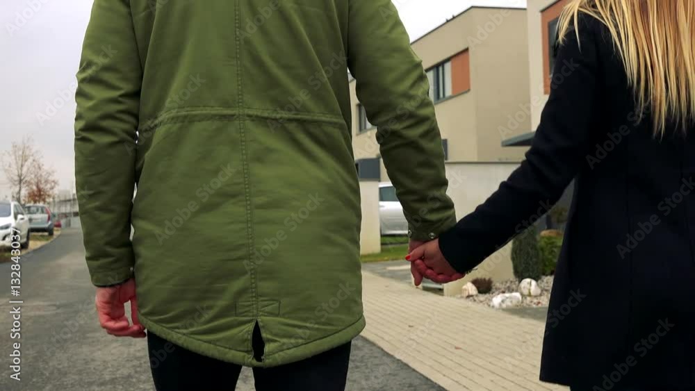 A couple from behind holds hands and walks down the street A couple from behind holds hands and walks down the street