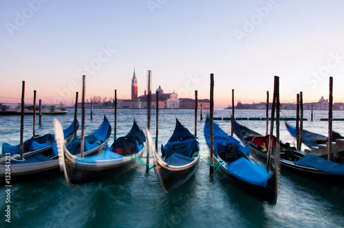 Traditional Venetian gondolas moored on the waterfront of Venice, Italy. Captured during sunset with motion blur. © Centaur