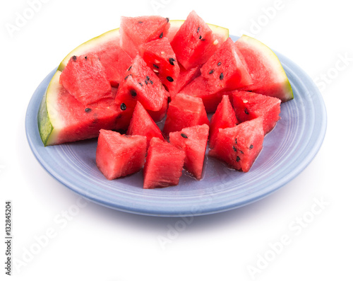 Watermelon slices and pieces on a blue plate, on white