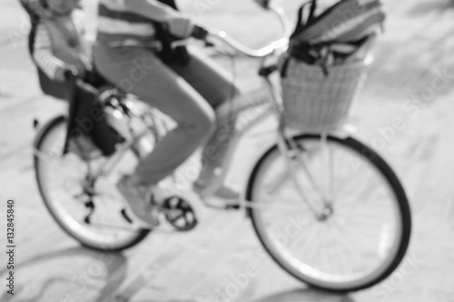 Defocused silhouette of active mother and child riding a bike together on oudroors background. Back side view image photo