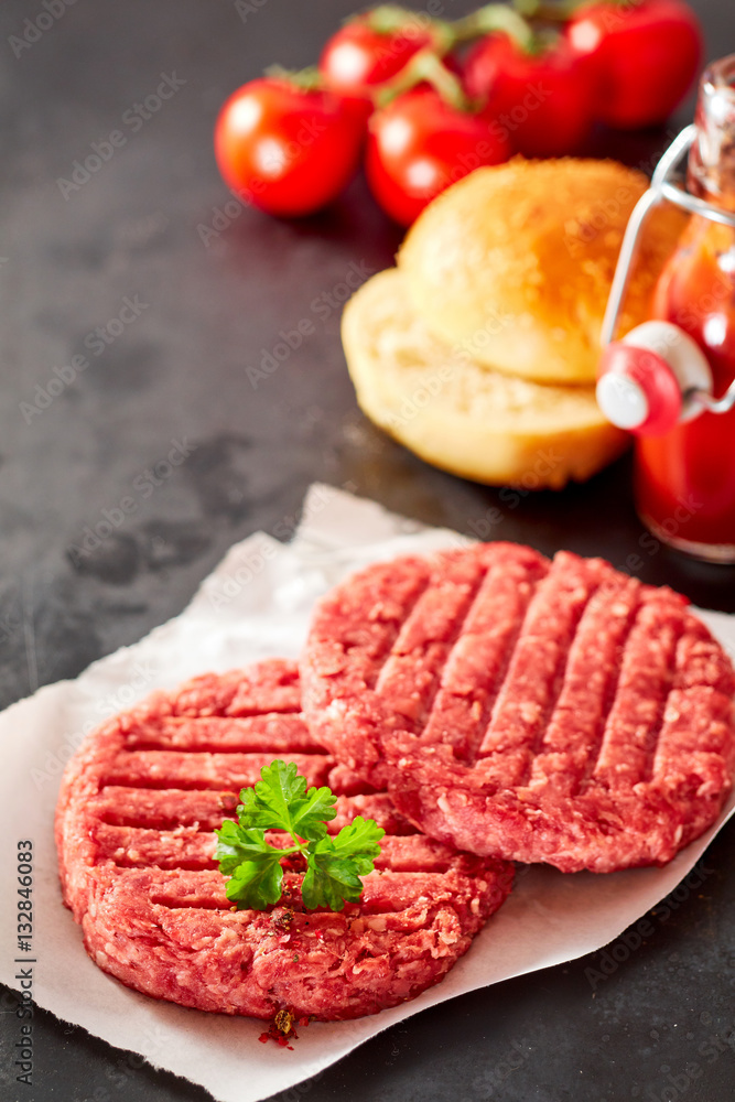 Pair of raw hamburger patties with toppings Pair of raw hamburger patties with toppings
