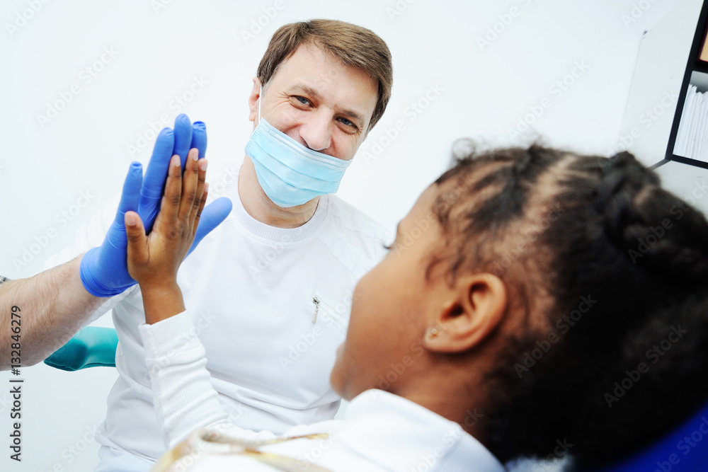 baby cute girl gives five dentist. African girl in the dentist's chair
