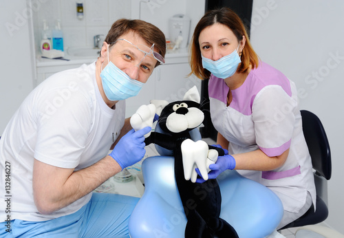 Male dentist and assistant girl examine teeth toy cat. Student medic dentist take an examination on a patient toy
