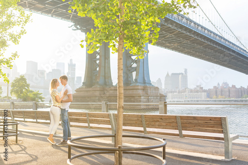 Young Beautiful Couple Hugging and Kissing Under the Brooklyn Bridge . New York City