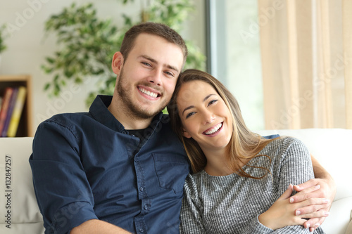 Happy couple looking at camera at home