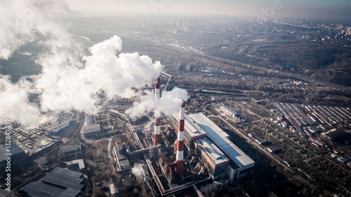 Air pollution by smoke coming out of two factory chimneys. Industrial zone in the city. Kiev, Ukraine, aerial view