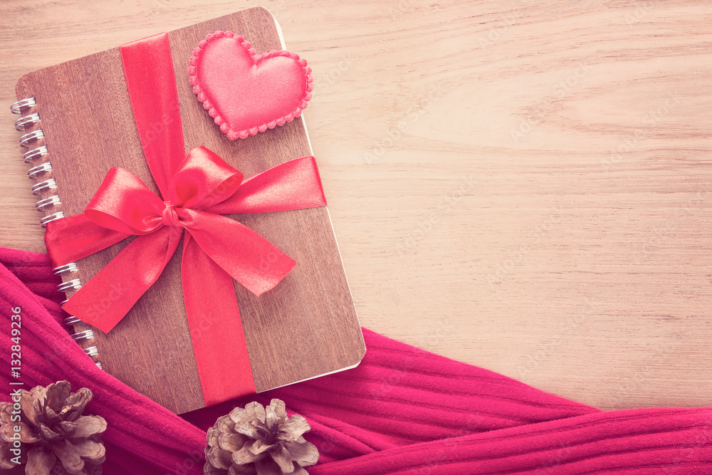 notebook wrapped with red ribbon and red felt hearts on wooden t