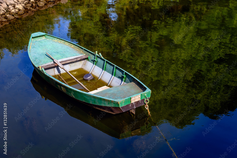 Green painted rowboat with a shallow layer of water