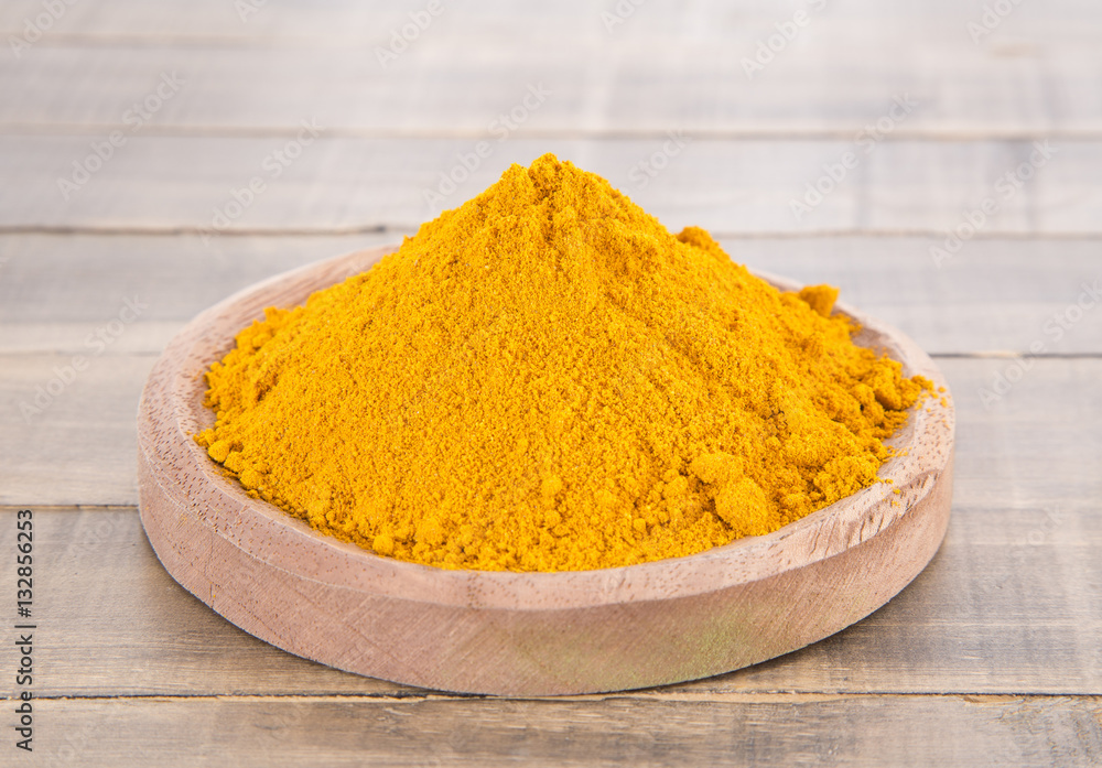 Turmeric powder on the wooden background - Curcuma longa Turmeric powder on the wooden background - Curcuma longa