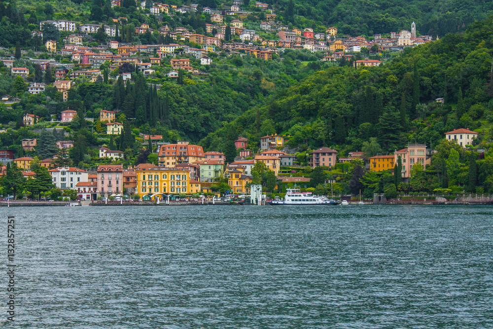 View on coast line of Lake Como, Italy, Lombardy region. Italian landscape, with Mountain and city with many colorful buildings on the shore