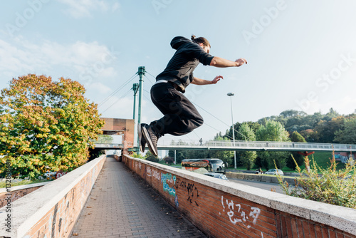Young beautiful caucasian man doing parkour outdoor in the city in autumn - stunt, acrobat, trick concept
