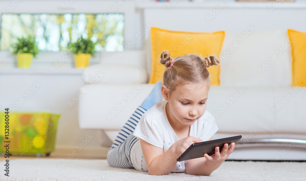 Pretty little girl using a digital tablet, looking and smiling Pretty little girl using a digital tablet, looking and smiling