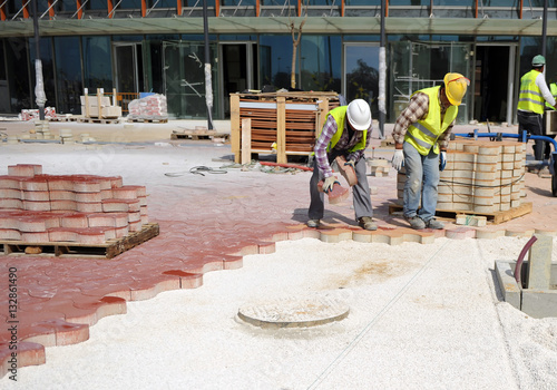 Construction workers paving a sidewalk with concrete pavers