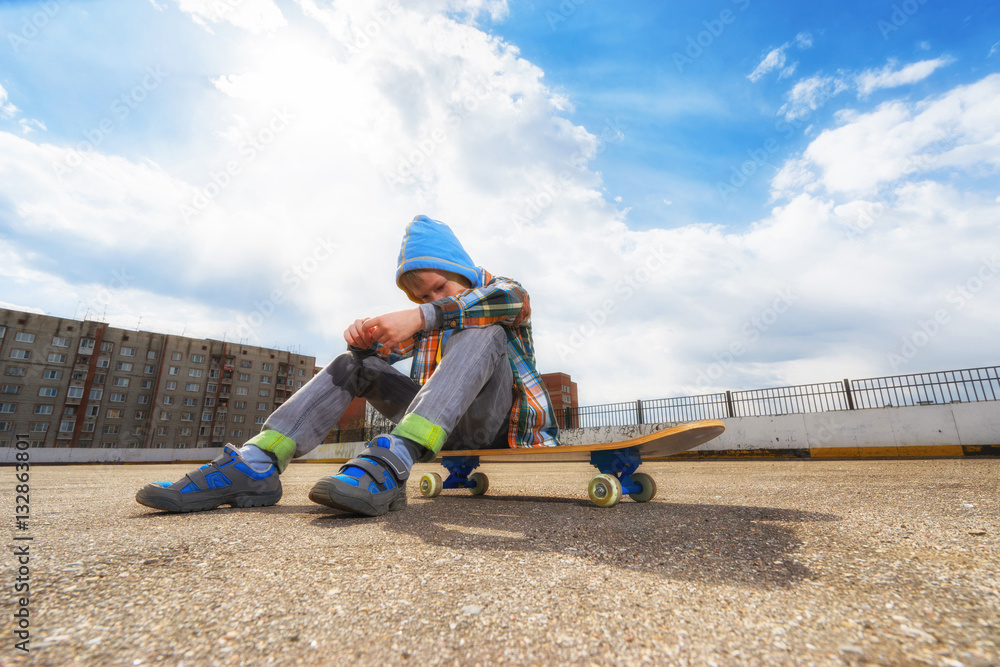 Boy on the street sitting on skateboard and thinking about something. Boy on the street sitting on skateboard and thinking about something.