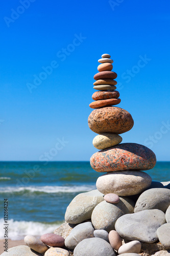 high pyramid of stones of different colors on the background of sea and blue sky