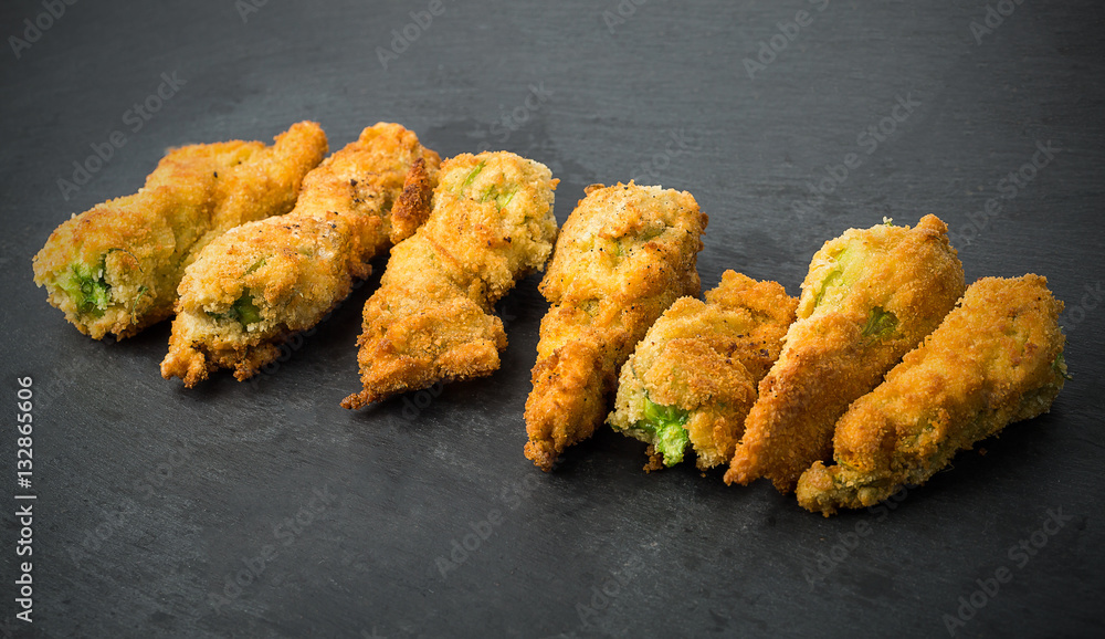 Fresh fried flower of zucchini on a natural black plate background Fresh fried flower of zucchini on a natural black plate background