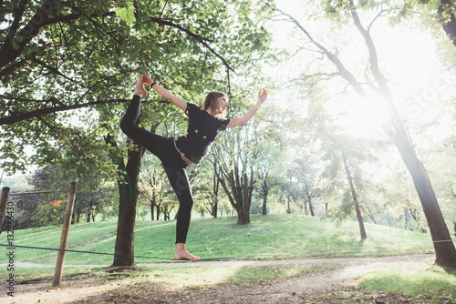 Woman balancing a tightrope or slackline outdoor in a city park in autumn - slacklining, balance, training concept photo