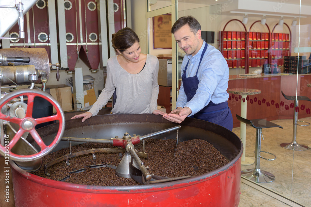 Man and woman looking into vat of coffee beans StockFoto Adobe Stock