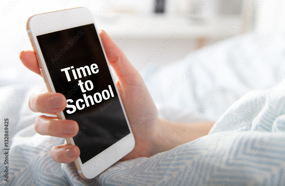 Time to School on smart phone screen, girl lying in bed Time to School on smart phone screen, girl lying in bed