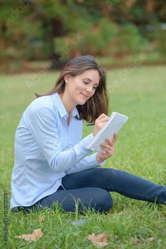 Woman sat in park writing in notepad © auremar