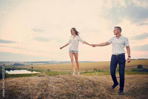 Happy couple holding hands and walking together outdoors at sunset