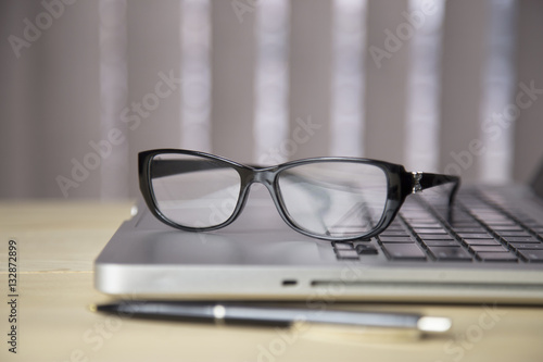 eyeglasses and notebook on wood background, black and white with