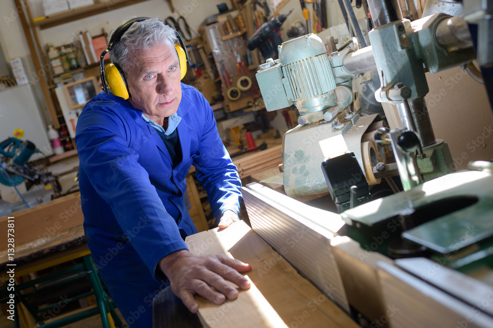 grey-haired carpenter using saw