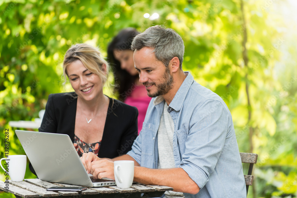 A smart couple is sitting at a terrace cafe and using a laptop A smart couple is sitting at a terrace cafe and using a laptop