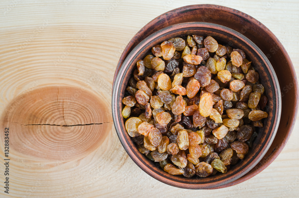 Dried Organic Raisin in Bowl on Wooden BackgroundClose-up. Dried Organic Raisin in Bowl on Wooden BackgroundClose-up.