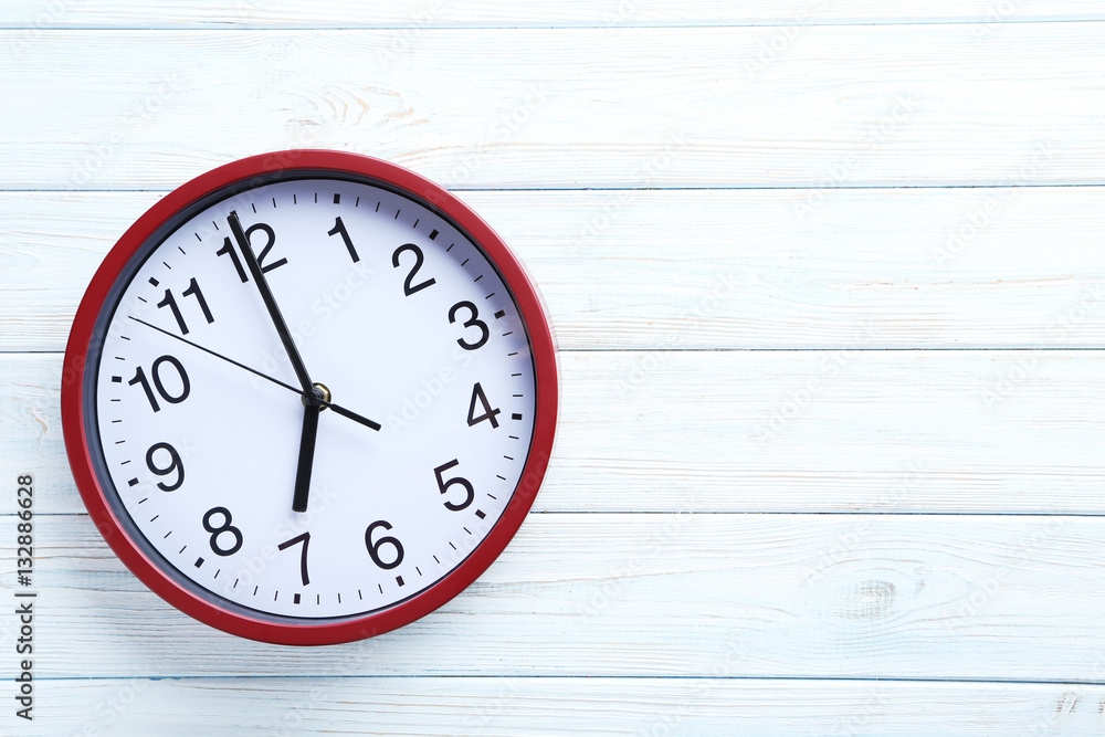 Red round clock on a white wooden table Red round clock on a white wooden table