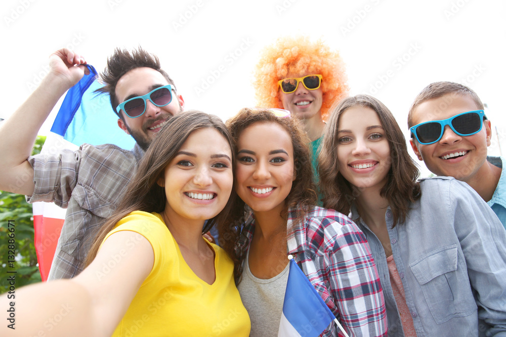 Fototapeta premium Emotional soccer fans with France flag making selfie, outdoors