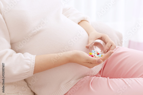 Closeup of pregnant woman holding plastic jar with pills
