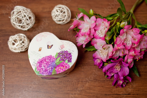 Bouquet of flowers with gift box on a wooden background