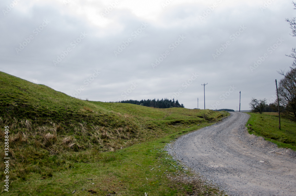 A winding gravel road leading to a grey sky A winding gravel road leading to a grey sky